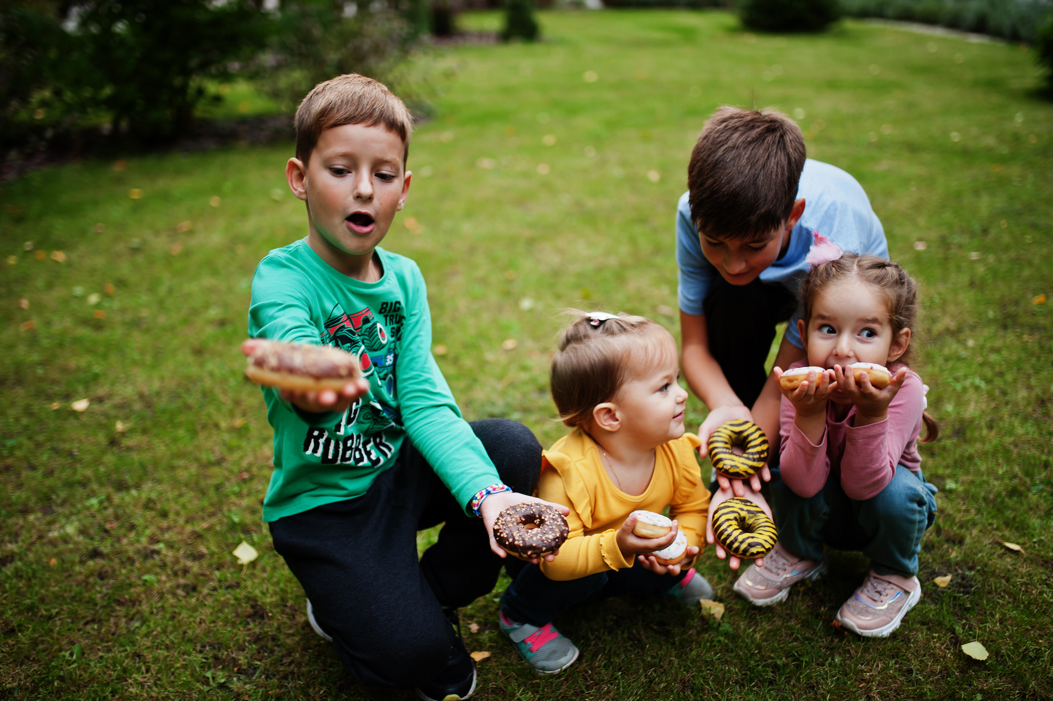 Four kids with doughnuts at evening yard