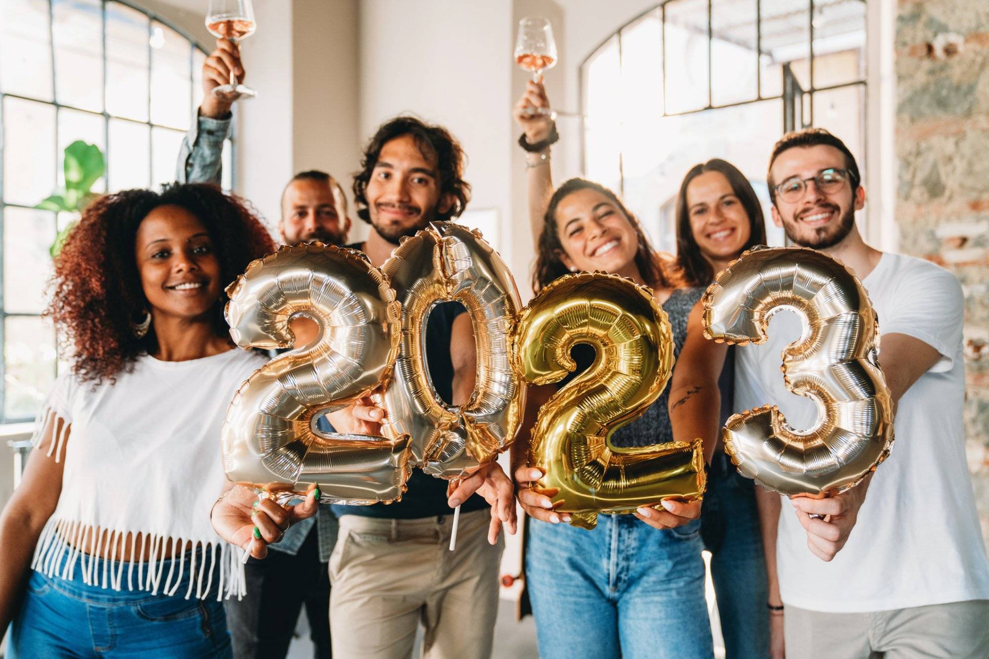 Friends are holding golden balloons to celebrate the new year 2023